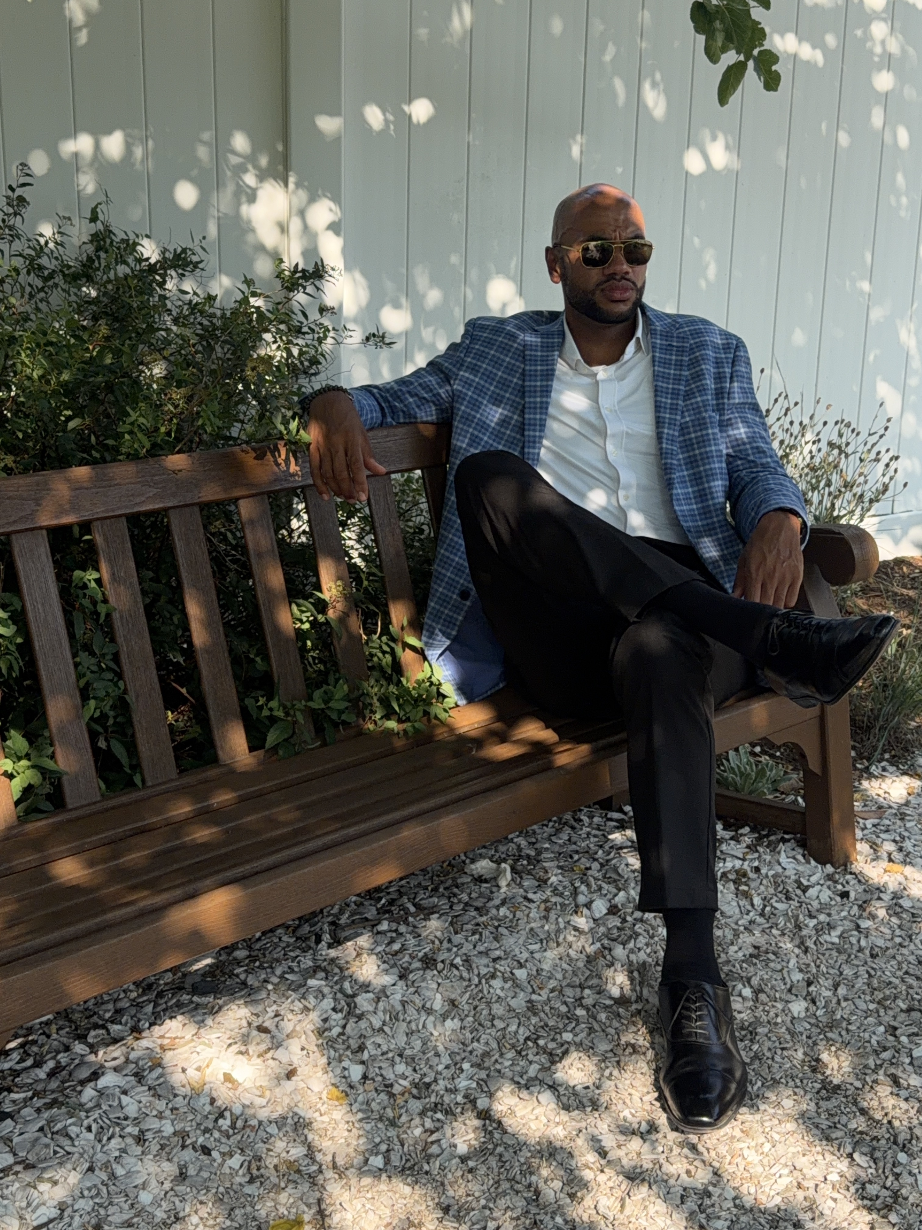 The guy allegedly in charge of Domination Athletics, sitting on a bench in a plaid blazer looking unbothered